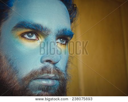 Portrait of a man with a blue make-up on his face. Stage make-up, like an alien, fantasy