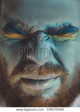 Portrait of a man with a blue make-up on his face. Stage make-up, like an alien, fantasy