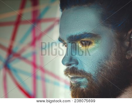 Portrait of a man with a blue make-up on his face. Stage make-up, like an alien, fantasy