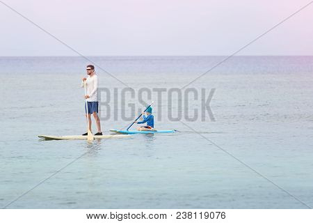 Happy Family Of Two, Father And Son, In Rashguards Enjoying Stand Up Paddleboarding St Sunset, Healt