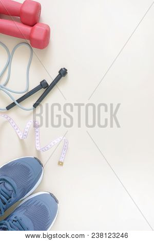 Vertical Fitness Background. On The Edge Lie Sports Shoes, A Skipping Rope And A Centimeter Tape. Pl