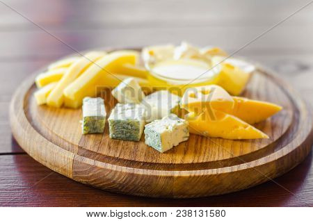 Cheese Plate. Assortment Of Various Types Of Cheese On Wooden Cutting Board.