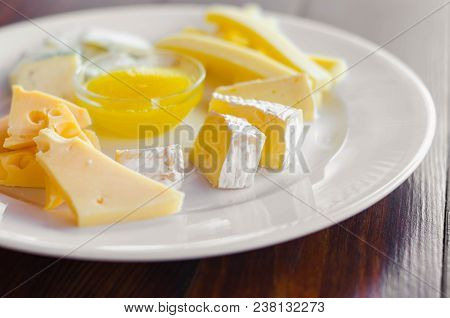 Cheese Plate. Assortment Of Various Types Of Cheese On Wooden Cutting Board.