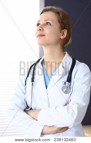 Woman Doctor With Crossed Arms Looking Up While Working In Hospital.