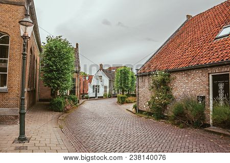 Drimmelen, Southern Netherlands - June 30, 2017. Charming And Quiet Street With Brick Rustic Houses 