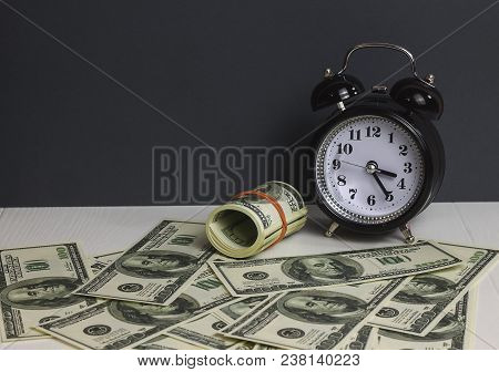 Retro Alarm Clock With  Stack Dollars  Wooden Table And Black Background As Long Term Savining Money