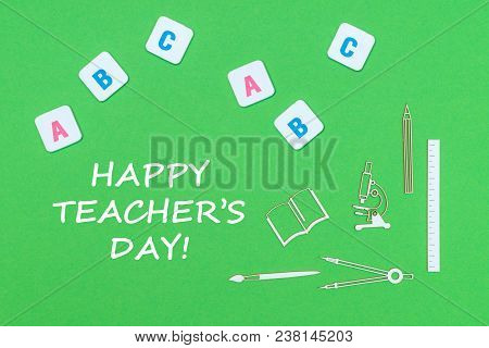Text Happy Teacher's Day, From Above Wooden Minitures School Supplies And Abc Letters On Green Backg