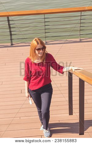 Cute Woman Walking Up The Stairs And Holding Cellphone.