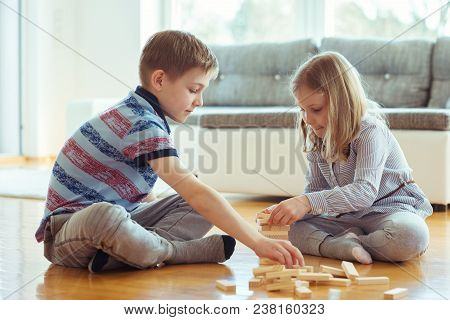 Two Happy Siblings Playing A Game With Wooden Blocks At Home