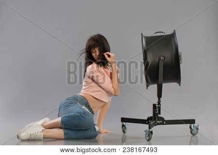 Young Brunette Woman With Raised By The Wind Machine. Studio Shot Over Gray Background