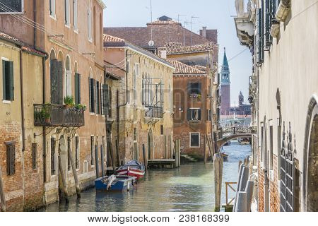 Boats On Acanal Among Old Old Houses And San Giorgio Maggiore On The Background In Venice, Italy.