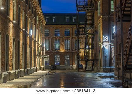 Night View Of The Old Industrial Quarter After The Rain. Iron Stairs, Tall Windows.