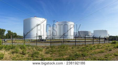 White Tanks In Tank Farm With Iron Staircase Under Blue Sky In Raunheim, Germany. The Depot Is Deliv