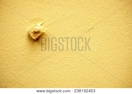 Metal Standoff On Yellow Concrete Wall Background.