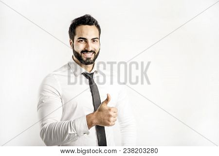 Portrait Of Bearded Eastern Man Dressed In White Shirt And Black Tie Shows Thumb Up Sign On Isolated