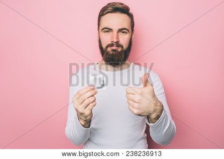 Handsome Man Is Holding A Condom In His Hand. Also He Is Showing His Big Thumb Up. He Prefers To Pro