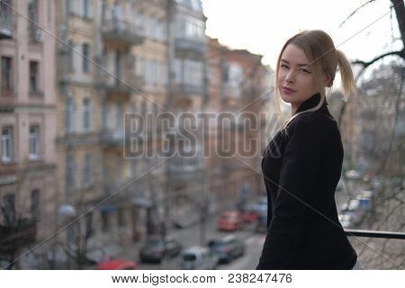 Portrait Of A Young Woman In A Black Suit Close-up Against A Background Of A Blurry City In The Rays