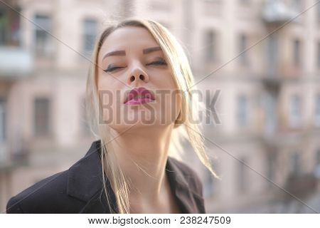 Portrait Of A Young Woman In A Black Suit Close-up Against A Background Of A Blurry City In The Rays