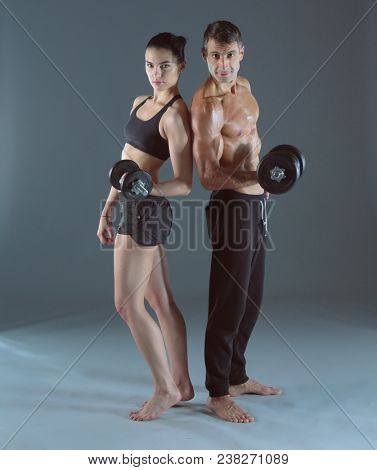 Athletic man and woman with a dumbells. Personal fitness instruc