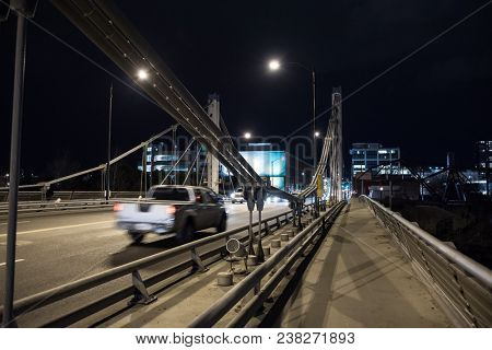 Modern steel bridge with traffic driving into the city center at night