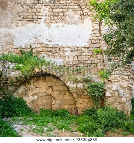 Ancient Immured Arch Covered With Plants, Within Old Sandstone Wall In Old Jaffa, Israel