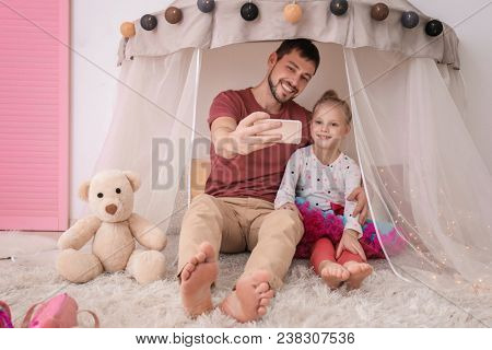 Father and his little daughter taking selfie in hovel at home