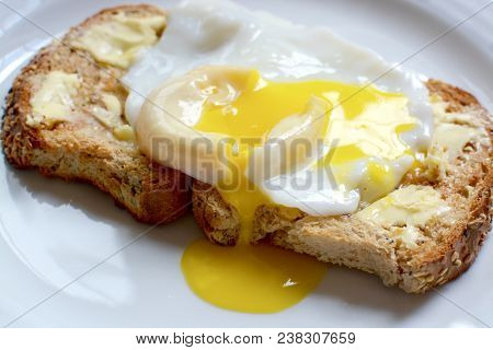 Runny Poached Egg On Brown Buttered Toast
