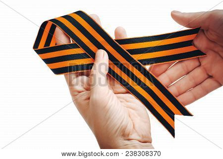 Orange And Black Striped Ribbon Symbol On May 9 In Hands. The Symbol Of The Great Victory Over The N