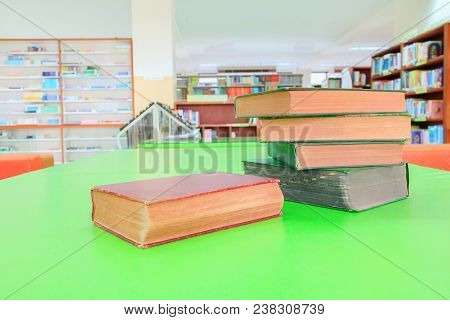 Old Book And Heap Treatise In School Library On Table Green. Blurry Bookshelves Background. Educatio