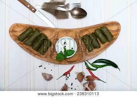 Dolma On Wooden Plate With Hot Peppers And Sour Cream On White Background. Caucasian Dish.