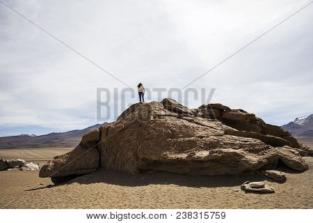 Young Woman At Ock Formations Of Dali Desert In Bolivia At Eduardo Avaroa Andean Fauna National Rese
