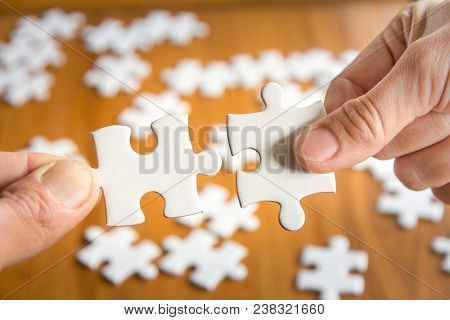 Close Up Of Hand Connecting Jigsaw Puzzle With Wooden Background, Business Solutions, Success And St