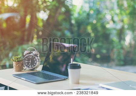 Comfortable Workplace, Office Desk With Blank Screen Laptop And Clock, Plant, Nature Light Bokeh Bac