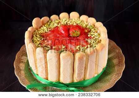French Charlotte Cake With Savoyardi Biscuits, Strawberries And Pistachio Nuts Decorated With A Gree
