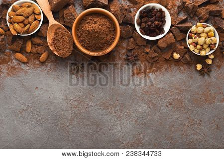 Dark Broken Chocolate Pieces On Dark Background, Cocoa Powder And Various Nuts In Bowls Closeup. Swe