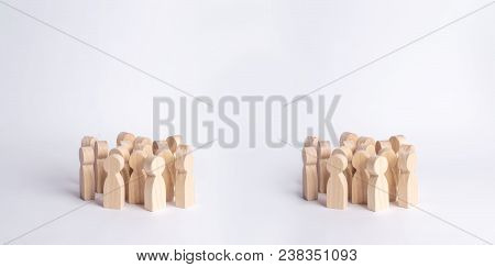 Two Crowds Of Wooden Figures Of People Are Standing On A White Background. The Concept Of Different 