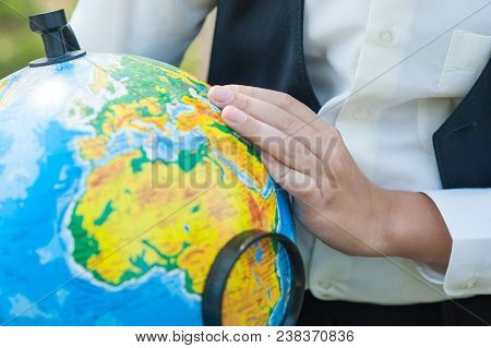 School Boy Looking At Russion Globe Sitting At A Desk On The Background Autumn Park