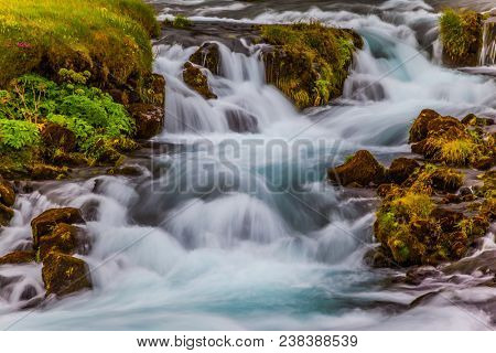 Boiling and rumbling cascading waterfall in Iceland. Wide picturesque valley along highway number one around the island. Travel in Iceland. Concept of active and extreme tourism