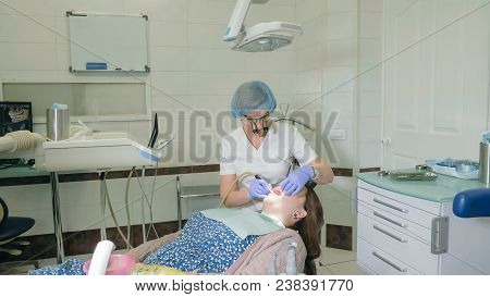 Woman At Dentist Clinic Gets Dental Treatment To Fill A Cavity In A Tooth. Dental Restoration And Co