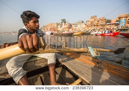 VARANASI, INDIA - MAR 26, 2018: Boatmen on a boat glides through water on Ganges river along shore of Varanasi. According to legends, Varanasi was founded by God Shiva about 5000 years ago.