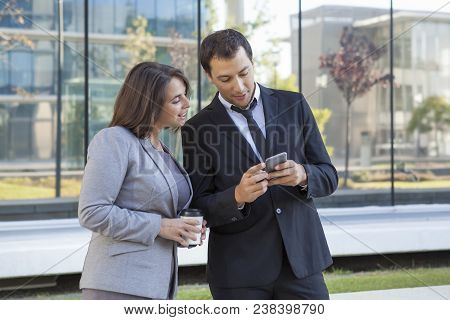 Cheerful Business Colleagues Reading Message On Smarphone While Resting Outdoors. Smiling Business P