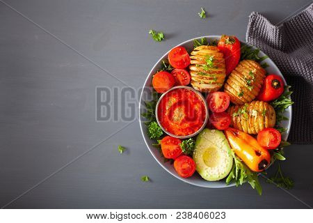 vegan buddha bowl. healthy lunch bowl with hasselback potato, avocado, tomato, bell peppers and pepper sauce
