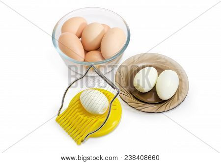 Manual Egg Slicer With Egg In It, Two Boiled Peeled Eggs On Saucer And Not Cleaned Eggs In A Glass B