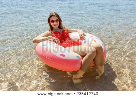 Young Woman In Red Swimsuit With Pink Cirkle On The Sea Beach.