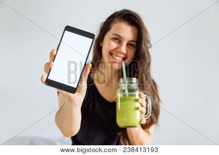 Young Pretty Woman Portrait Drink Smoothie And Show Shite Screen In Smartphone. White Background. Co