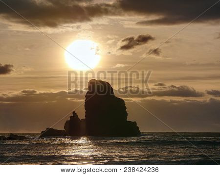 Sharp Silhouette Of A Cliff Against The Background Of Sunset. Sea Waves Break On The Rocks. Talisker