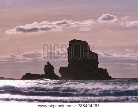 Cloudy Evening On Rocky Shore At Sunset. Sunset Mirroring In  Sea Water And Large Cracked Rocks With