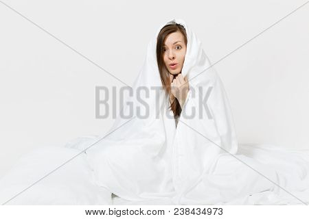 Young Brunette Woman Sitting In Bed With White Sheet, Pillow, Wrapping In Blanket On White Backgroun