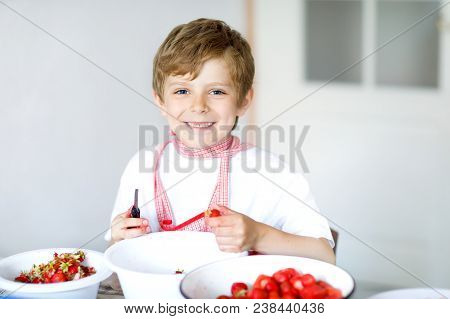 Little Blond Kid Boy Helping And Making Strawberry Jam In Summer. Funny Child Cleaning Berries And P