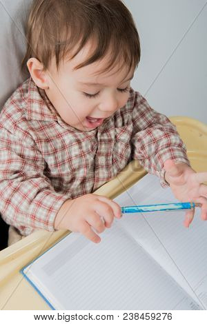 Little baby boy is playing with pen and note book
